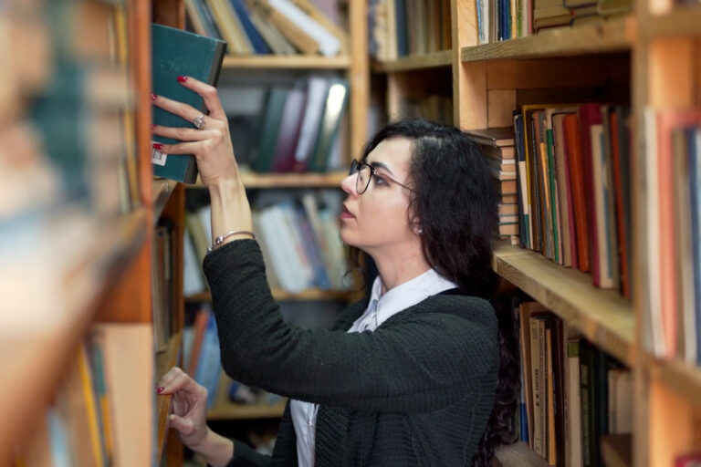 student in library pulling out a book