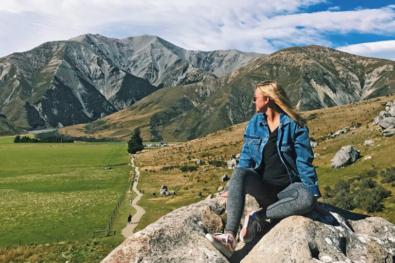 student sitting on mountain range in foreign country